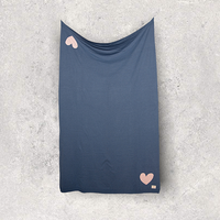 Stretched blue organic cotton travel blanket with pink hearts on a white surface