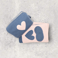 Marine blue and pink organic cotton travel blanket and blue eye mask set with a travel pouch for women on a white textured surface
