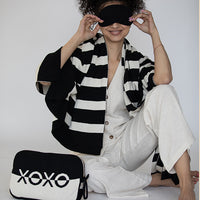 Person wearing a black and white striped blanket with a 'XOXO' pouch on a white background