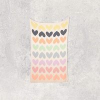 Hanging cotton travel blanket with colourful hearts on a textured surface.