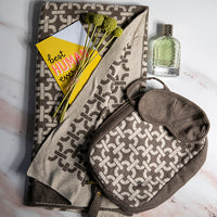 Organic cotton travel blanket set in brown with a link pattern, including a soft blanket, sleep mask, and compact zip bag.