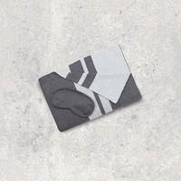 Set of light and dark gray organic cotton travel blanket with stripes and a matching dark grey eye mask on a light gray surface.
