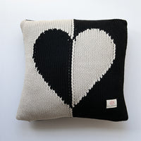 Knitted cotton pillow with black and white heart design on a light gray background.