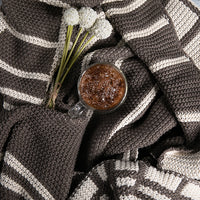 Cup of coffee with flowers on a double moss-knit dark brown cotton throw blanket.
