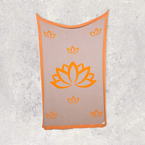 Neon orange and brown cotton blanket with orange lotus flower design on a textured gray background.