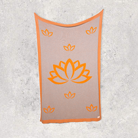 Neon orange and brown cotton blanket with orange lotus flower design on a textured gray background.