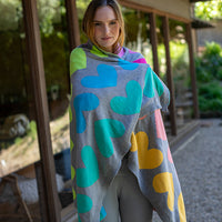 Woman wrapped in a warm colourful grey blanket with heart patterns in the outdoors.