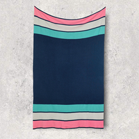 Striped navy cotton blanket with neon blue, pink, and white pattern hung on a textured surface