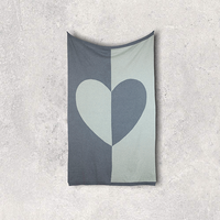 Grey reversible organic cotton blanket with a heart design on a textured surface.