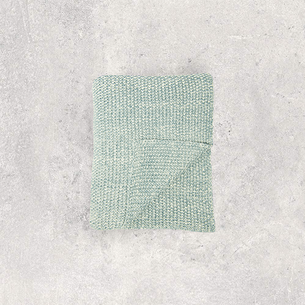Moss knitted throw blanket on a textured gray background.