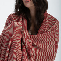Woman with shoulder length hair wearing a red and white ribbed and textured comfortable throw blanket.