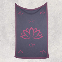 Dark gray travel blanket with pink lotus flower design on a textured white background.