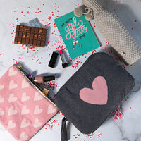 Grey cotton travel blanket pouch with a pink heart motif and a make-up bag with lip stick and a knitted wine sleeve.