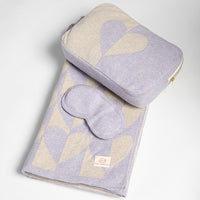 Set of lavender eye mask, blanket and pouch with heart design on a light gray background.