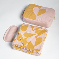 Pink and mustard patterned cotton blanket with matching pouch and eye mask on a light gray background.