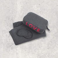 Gray cotton travel blanket set with dark grey 'LOVE' pouch, eye mask, and gloves on a light gray background.
