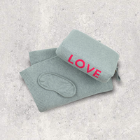 Light grey travel blanket set with 'LOVE' in red with a matching eye mask on a textured gray surface.