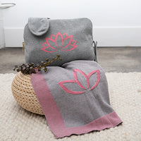 Gray blanket with pink lotus design on a woven basket.