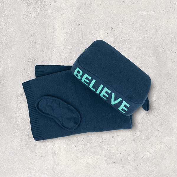 Navy blue cotton travel blanket and pouch with 'BELIEVE' in sea green text on a light gray background.