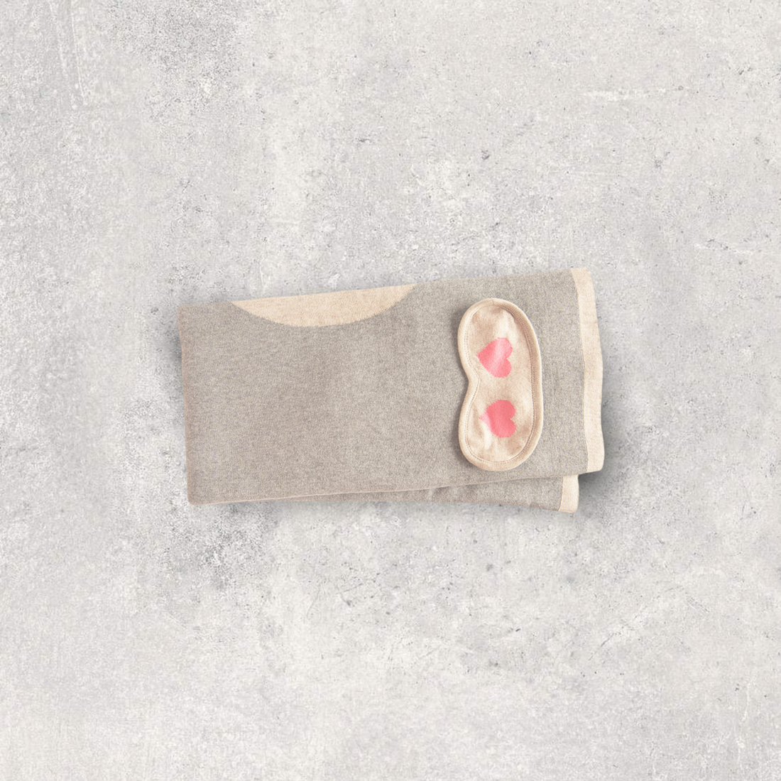 Soft and compact organic cotton travel blanket with a sleep mask with two pink hearts.