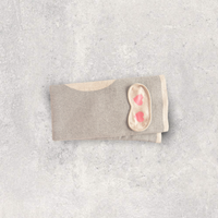 Soft and compact organic cotton travel blanket with a sleep mask with two pink hearts.