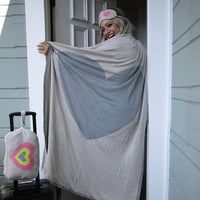 Woman wearing the Crazy Hearts Capri travel set, with the pink heart eye mask on and wrapped in the soft blanket.