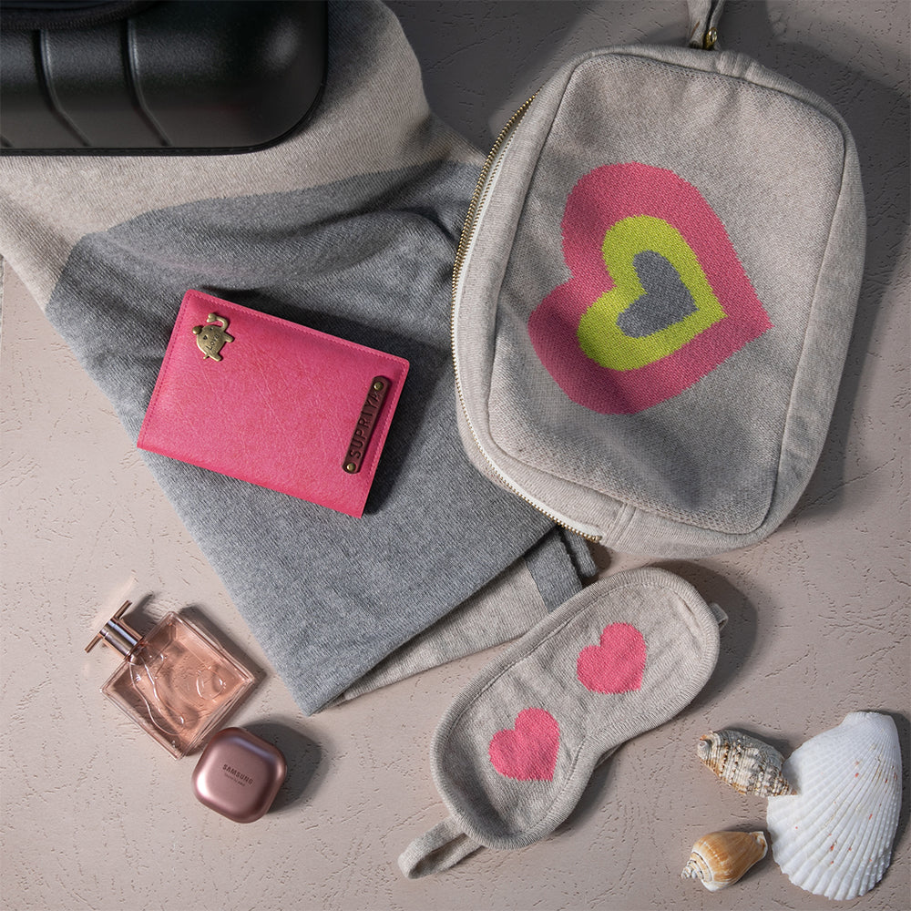 Grey compact travel organiser bag with a multi-color heart design, containing the Crazy Hearts organic cotton blanket and eye mask and a passport cover