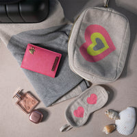 Grey compact travel organiser bag with a multi-color heart design, containing the Crazy Hearts organic cotton blanket and eye mask and a passport cover