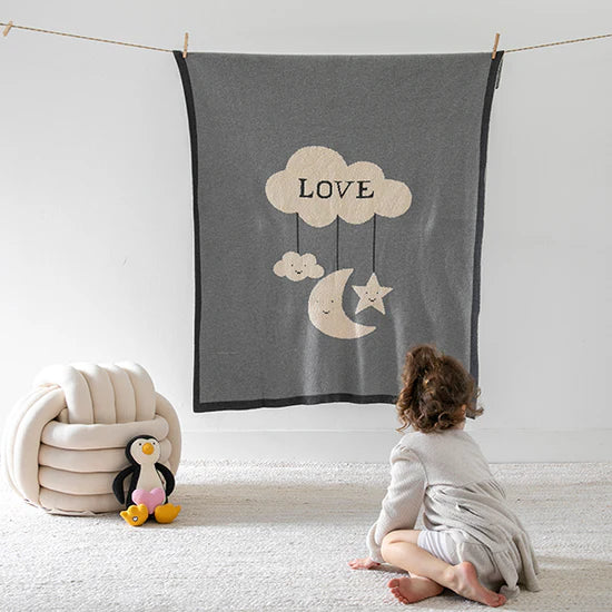 An infant looking at a grey organic cotton baby blanket from Pink Lemonade.