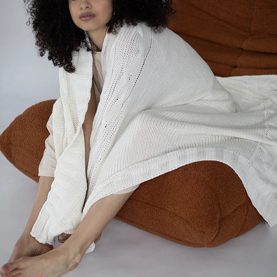 Model wrapped in a white Pink Lemonade Classic organic cotton knit throw blanket.