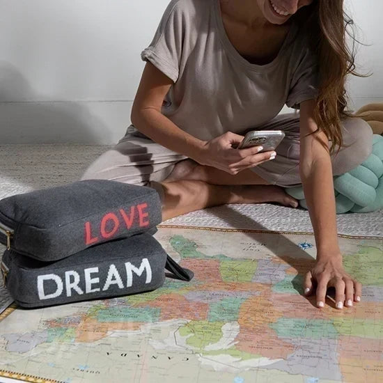 Pink Lemonade Words Love organic cotton travel blanket and matching eye mask set beside a traveler planning a trip with a map.
