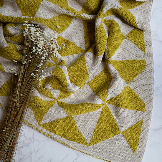Pink Lemonade Trikona organic cotton knit throw blanket with dried flowers. 