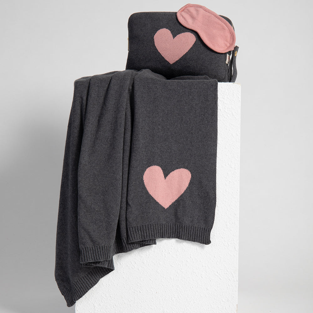 Gray reversible cotton travel blanket with pink heart designs on a white surface