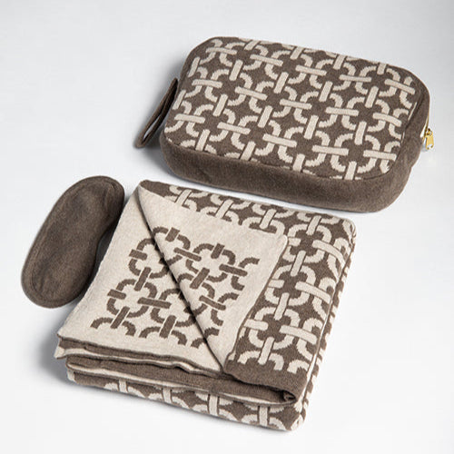 Brown and beige patterned travel pouch and folded blanket on a light gray background