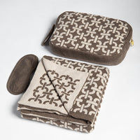 Brown and beige patterned travel pouch and folded blanket on a light gray background