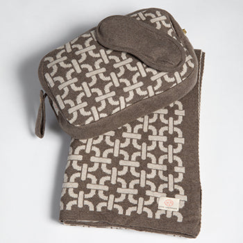 Patterned travel bag with a geometric chain design and cotton eye mask on a white background