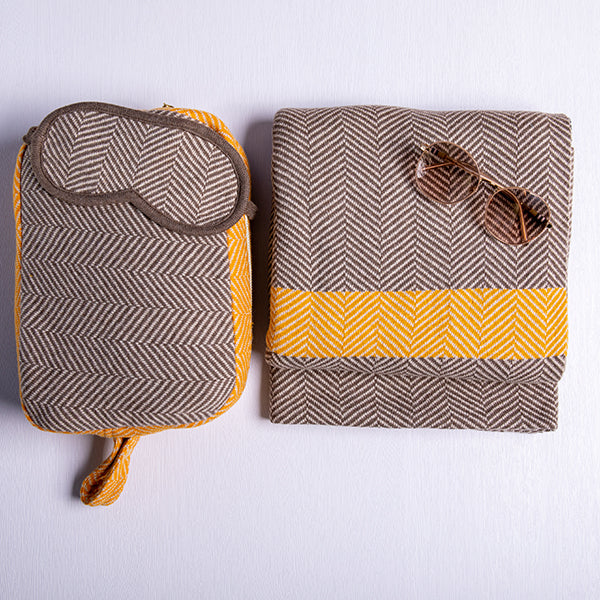 Brown chevron pattern travel set with a matching eye mask, pouch, and blanket on a white background with sunglasses