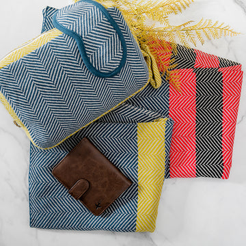 Set of a chevron cotton travel blanket, eye mask and zip bag with a wallet on a white surface
