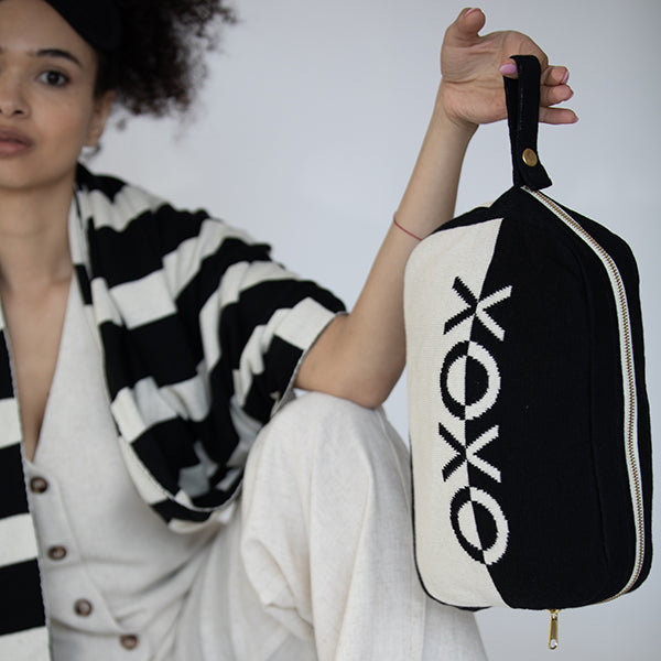 Person holding a black and white travel pouch with 'Koko' branding against a neutral background