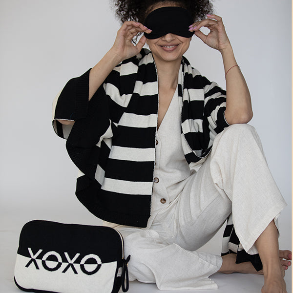 Person wearing a black and white striped blanket with a 'XOXO' pouch on a white background