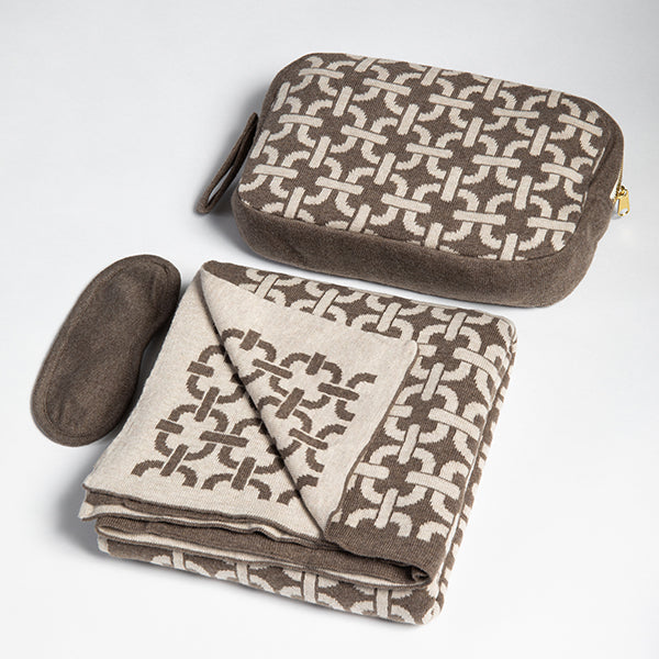 Brown and beige chain link patterned travel pouch and folded blanket on a light gray background.