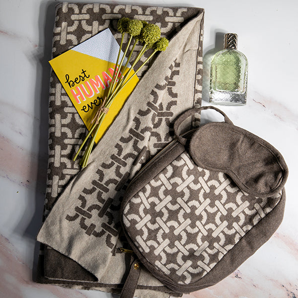 Organic cotton travel blanket set in brown with a link pattern, including a soft blanket, sleep mask, and compact zip bag.