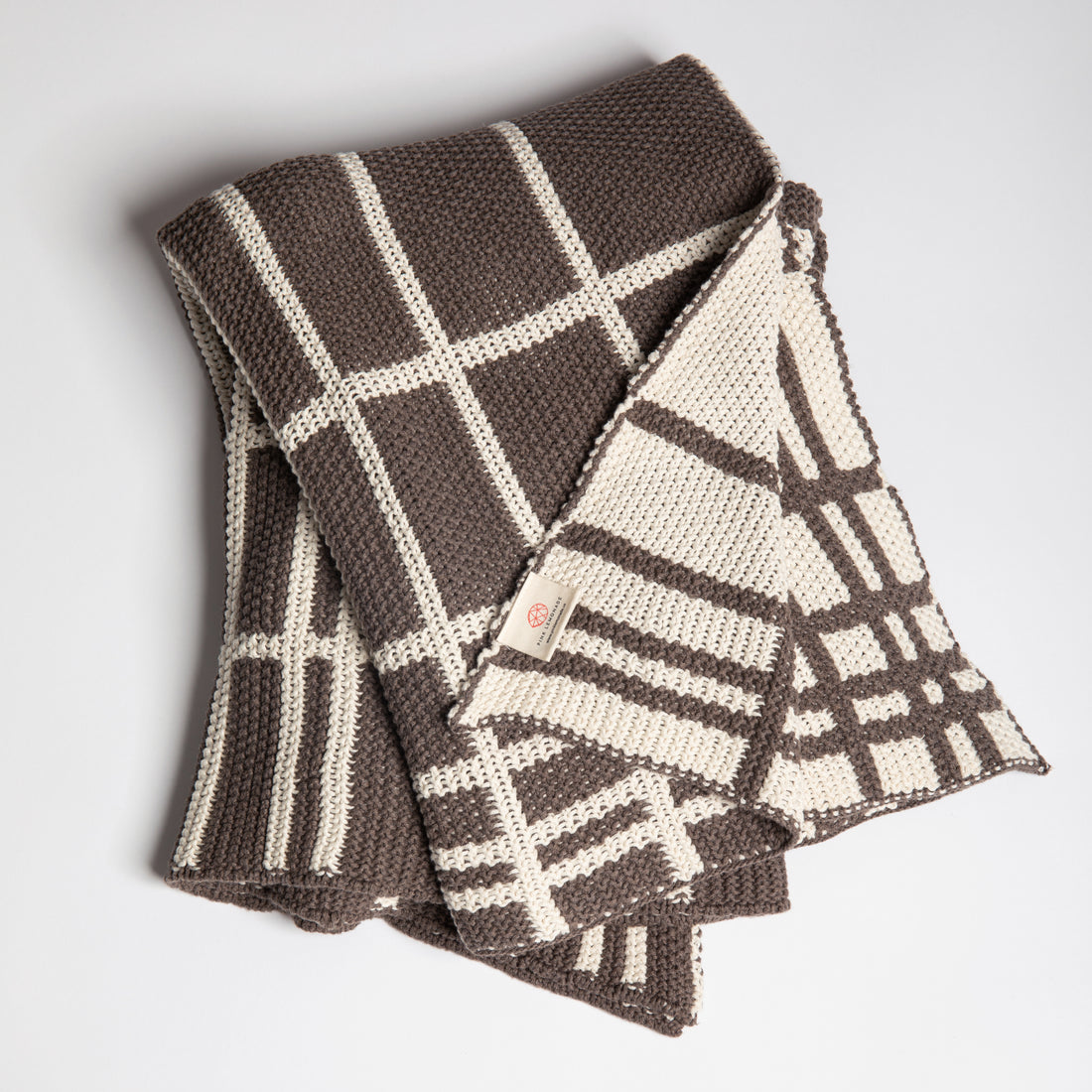 Moss-knit cotton throw blanket with brown and white plaid pattern on a light gray background.