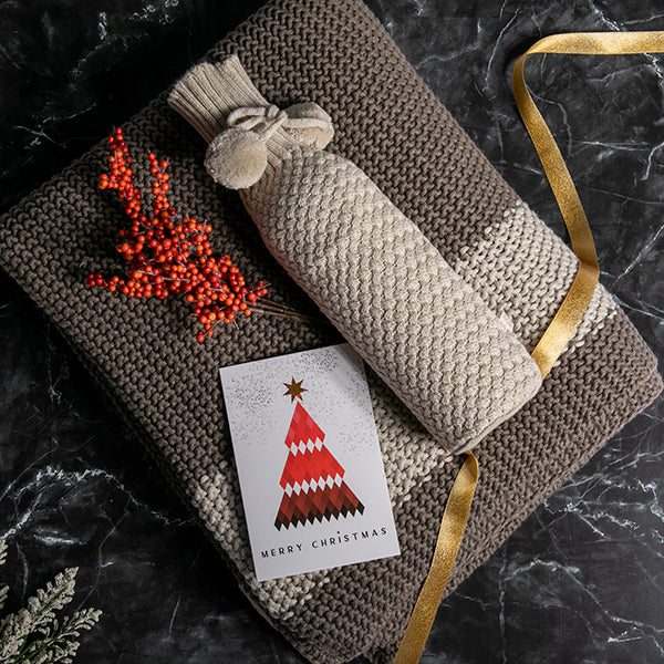 Knitted cotton wine sleeve with a matching moss-knit throw blanket with a gold ribbon and Christmas card with mistletoe.