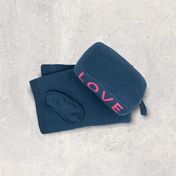 Navy blue pouch with 'LOVE' text in pink and matching cotton travel blanket and soft eye mask on a light gray background