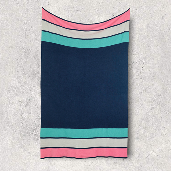 Striped navy cotton blanket with neon blue, pink, and white pattern hung on a textured surface