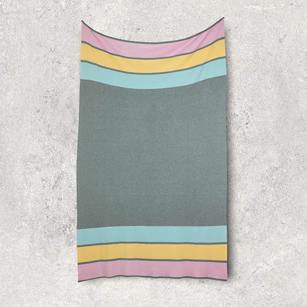 Stretched travel blanket with colorful stripes on a textured gray background.