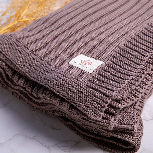 Folded espresso brown knitted blanket with a Pink Lemonade brand label on a marble surface.