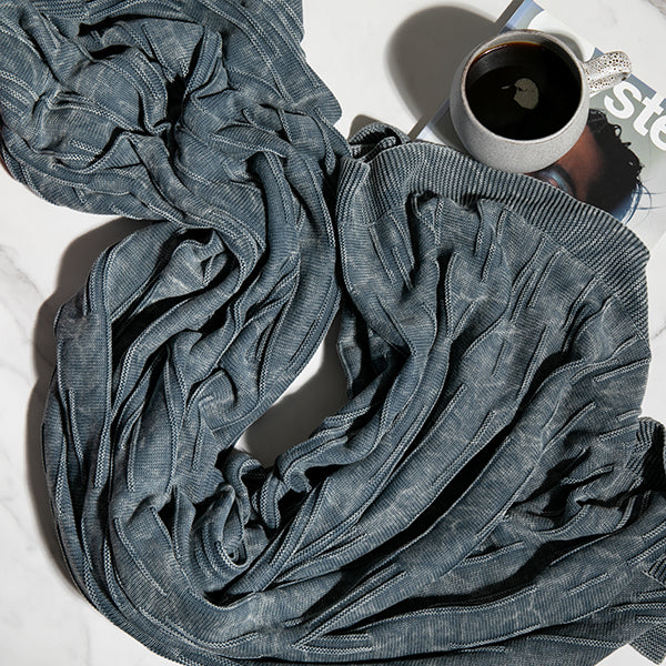 Flintstone blue washed cotton throw blanket with a cup of coffee and a book on a white surface