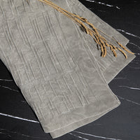 Stone grey washed throw with a geometric pattern on a dark surface.